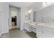 Well-lit bathroom featuring double sinks and vanity, alongside entry to the walk-in closet at 12349 N 145Th Ave, Surprise, AZ 85379