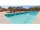 A long community swimming pool with an adjacent clubhouse and shaded lounge chairs at 12349 N 145Th Ave, Surprise, AZ 85379