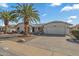 Single-story home with a landscaped front yard, two palm trees, and a two-car garage at 19611 N Stardust Blvd, Sun City West, AZ 85375