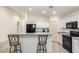 Modern kitchen with white cabinets, black appliances, and an island with seating at 25740 W Watkins St, Buckeye, AZ 85326