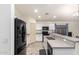 Modern kitchen with white cabinets, black appliances, and an island with seating at 25740 W Watkins St, Buckeye, AZ 85326