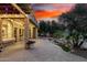 Paver patio showcases a charming pergola, water feature, and outdoor kitchen under a colorful dusk sky at 28247 N 128Th Dr, Peoria, AZ 85383