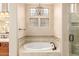 Bright bathroom features soaking tub, decorative tile, seamless shower door, and glass block window at 28247 N 128Th Dr, Peoria, AZ 85383