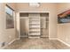 An empty bedroom with large windows, ceiling fan, and open closet with mounted shelving racks at 28247 N 128Th Dr, Peoria, AZ 85383