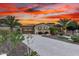 Charming single-story home with lush landscaping, stone accents, and a brick driveway under a dramatic sunset sky at 28247 N 128Th Dr, Peoria, AZ 85383