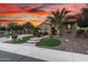 Charming single-story home with lush landscaping, stone accents, and a brick driveway under a dramatic sunset sky at 28247 N 128Th Dr, Peoria, AZ 85383