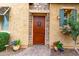 Elegant wooden front door with stone surround, potted flowers, and stucco facade at 28247 N 128Th Dr, Peoria, AZ 85383