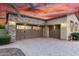 Three-car garage with stone accents and brick-paved driveway under a vibrant sunset at 28247 N 128Th Dr, Peoria, AZ 85383