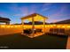 String lights decorate this backyard patio with a firepit surrounded by seating with privacy wall and turf at 4752 S Orbit Ave, Mesa, AZ 85212