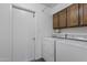 Functional laundry room featuring a washing machine, dryer, overhead cabinets, and a convenient entrance door at 5045 W Mescal St, Glendale, AZ 85304