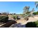 Landscaped backyard with a stone patio, iron fence, and golf course view at 7740 E Gainey Ranch Rd # 13, Scottsdale, AZ 85258