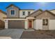 Charming two-story home featuring a gray garage door and a red front door, complemented by neutral-toned siding and gravel landscaping at 9227 E Sector Dr, Mesa, AZ 85212