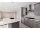 Stylish kitchen boasts a quartz island, gray cabinetry, stainless steel range hood, and wood-look flooring, open to the living area at 9227 E Sector Dr, Mesa, AZ 85212