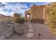 Stone pathway leads to a unique stucco and stone home with desert landscaping at 10473 E Greythorn Dr, Scottsdale, AZ 85262