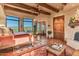 Main bedroom with terracotta floors, wooden beams, and a cozy sitting area at 10473 E Greythorn Dr, Scottsdale, AZ 85262