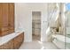 Bright bathroom featuring wood cabinets, marble walls, a freestanding tub, and a walk-in closet at 19910 N 84Th St, Scottsdale, AZ 85255