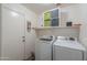 Well-equipped laundry room with modern washer and dryer, ample storage shelves, and convenient access to the outdoors at 35598 N Murray Grey Dr, San Tan Valley, AZ 85143