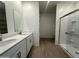 Bathroom features dual sinks with white countertops, a walk-in shower, and wood-look flooring at 46905 W Old Timer Rd, Maricopa, AZ 85139