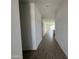 Long hallway with wood-look tile, leading to an open-concept living area, freshly painted white at 46905 W Old Timer Rd, Maricopa, AZ 85139