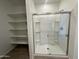Walk-in shower with glass enclosure, built-in shelves, and adjacent walk-in closet at 46905 W Old Timer Rd, Maricopa, AZ 85139