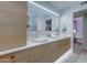 Bathroom featuring double sinks with wood cabinetry, quartz countertops, and access to the bedroom at 5432 E Paradise Dr, Scottsdale, AZ 85254