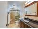 Well-lit bathroom with a granite countertop vanity, a glass-enclosed shower, and neutral tile flooring at 6720 E Phelps Rd, Scottsdale, AZ 85254