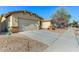 View of the garage and driveway with desert landscaping at 14400 N 136Th Ln, Surprise, AZ 85379