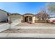 Front view of a tan house with a two-car garage and desert landscaping at 14400 N 136Th Ln, Surprise, AZ 85379