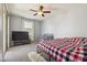 Cozy bedroom featuring a bed, crib, large window with natural light, and a wall-mounted TV at 17749 W Woodrow Ln, Surprise, AZ 85388