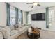 Bright living room with a ceiling fan, plush sofa, large windows, and a sleek wall-mounted TV at 17749 W Woodrow Ln, Surprise, AZ 85388