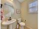 Elegant powder room with pedestal sink, toilet, and window with plantation shutters at 17842 W Chuckwalla Canyon Rd, Goodyear, AZ 85338