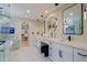 Elegant bathroom featuring double sinks, marble floors, crystal chandelier and glass enclosed shower and tub at 18 W Kaler Dr, Phoenix, AZ 85021