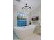 Stunning bathroom featuring a modern tub, chandelier, mounted TV, and a bright window at 18 W Kaler Dr, Phoenix, AZ 85021