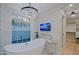 Bright bathroom features a modern tub, chandelier, mounted TV, and view to the walk-in closet at 18 W Kaler Dr, Phoenix, AZ 85021