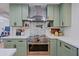 Modern kitchen with sage cabinets, stainless steel range and stainless steel hood vent at 18 W Kaler Dr, Phoenix, AZ 85021