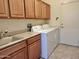 Bright laundry room, washer, dryer, cabinets, and sink at 18328 N Avalon Ln, Surprise, AZ 85374