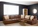 Living room with a brown leather sectional sofa and a dark-colored wall at 21282 E Swan Dr, Queen Creek, AZ 85142