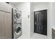 This laundry room features a stacked washer and dryer, a storage cabinet, and a black door at 25150 N Windy Walk Dr # 11, Scottsdale, AZ 85255