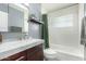 Well-lit bathroom with a shower-tub combination featuring white tile, a dark vanity, and neutral wall color at 2808 N Granite Reef Rd, Scottsdale, AZ 85257