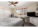 This bedroom features a ceiling fan, a large window with a view, a closet, built in shelving, and a large bed with a grey quilt at 6422 W Garden Dr, Glendale, AZ 85304