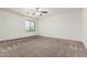 Empty bedroom features neutral carpet, ceiling fan, and a window with a view at 7461 W Tumblewood Dr, Peoria, AZ 85382