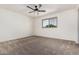 A bright bedroom featuring neutral carpeting, a ceiling fan with light fixture, and a window view at 7461 W Tumblewood Dr, Peoria, AZ 85382