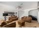 Open concept living room with tile floors, ceiling fan, TV and brown leather furniture at 7461 W Tumblewood Dr, Peoria, AZ 85382