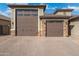 Paver driveway leads to garages with stone accents and carriage doors with glass windows at 7718 W Raymond St, Phoenix, AZ 85043