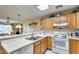 Oak kitchen with white appliances, double sink, and partial living room view at 14300 W Bell Rd # 502, Surprise, AZ 85374