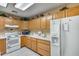 Bright kitchen with oak cabinets, white appliances, and a view of the fridge at 14300 W Bell Rd # 502, Surprise, AZ 85374