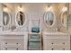 Elegant bathroom with double sinks, oval mirrors, and marble tile at 14861 W Verde Ln, Goodyear, AZ 85395