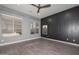 Bright bedroom with dark accent wall, ceiling fan, and wood-look flooring at 16351 W Yucatan Dr, Surprise, AZ 85388