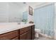 Bathroom with wood cabinets and a teal shower curtain at 17022 W Echo Ln, Waddell, AZ 85355