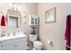 Cozy bathroom features vanity with white sink, a round mirror, and a white toilet with decor at 19308 W Jefferson St, Buckeye, AZ 85326